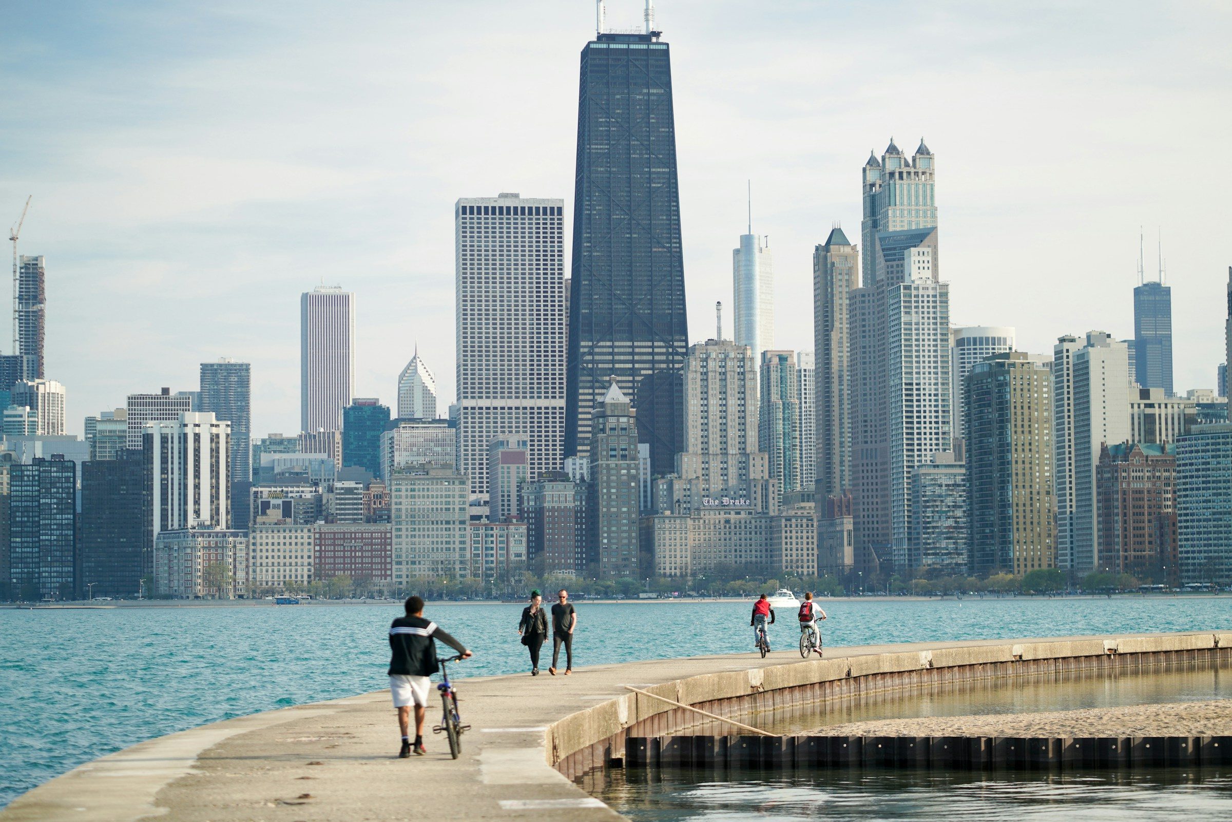 People walking and biking on a lakefront pier with the Chicago skyline behind them