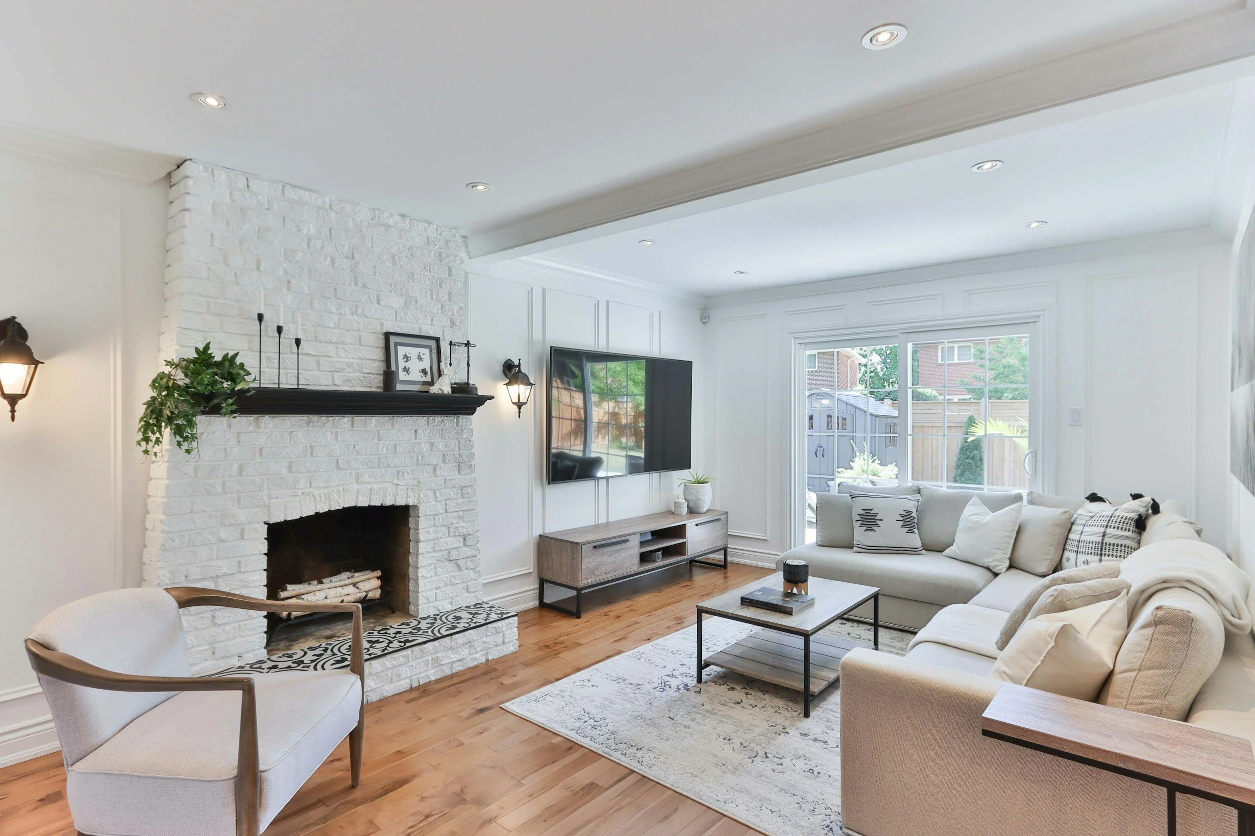 A bright living room with a white brick fireplace and a light sectional sofa